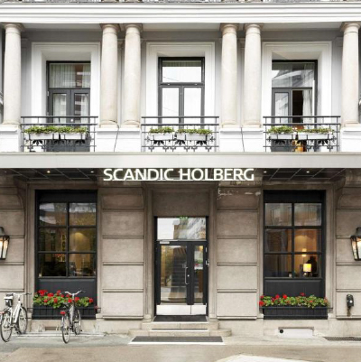 Street view of a hotel entrance. Flowers under windows on ground floor and 1st floor balconies.