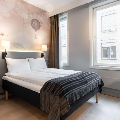 Hotel room with double bed and window. Neighbouring building visable through the window.