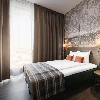 Modern hotel room with double bed and high window and curtains.