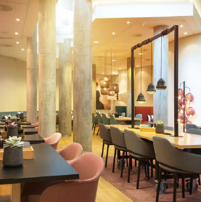 Modern dining room with columns, wooden tables and hanging pendant lights over tables.